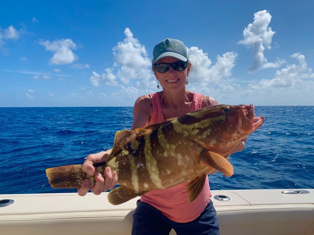 Angler holding a colorful grouper caught offshore using live bait enhanced with Keys Feeds premium fish food